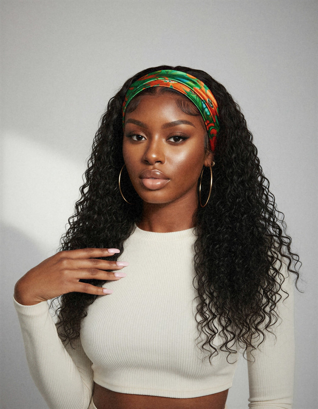 Perruque bandeau bouclée deep wave portée de face, fond studio