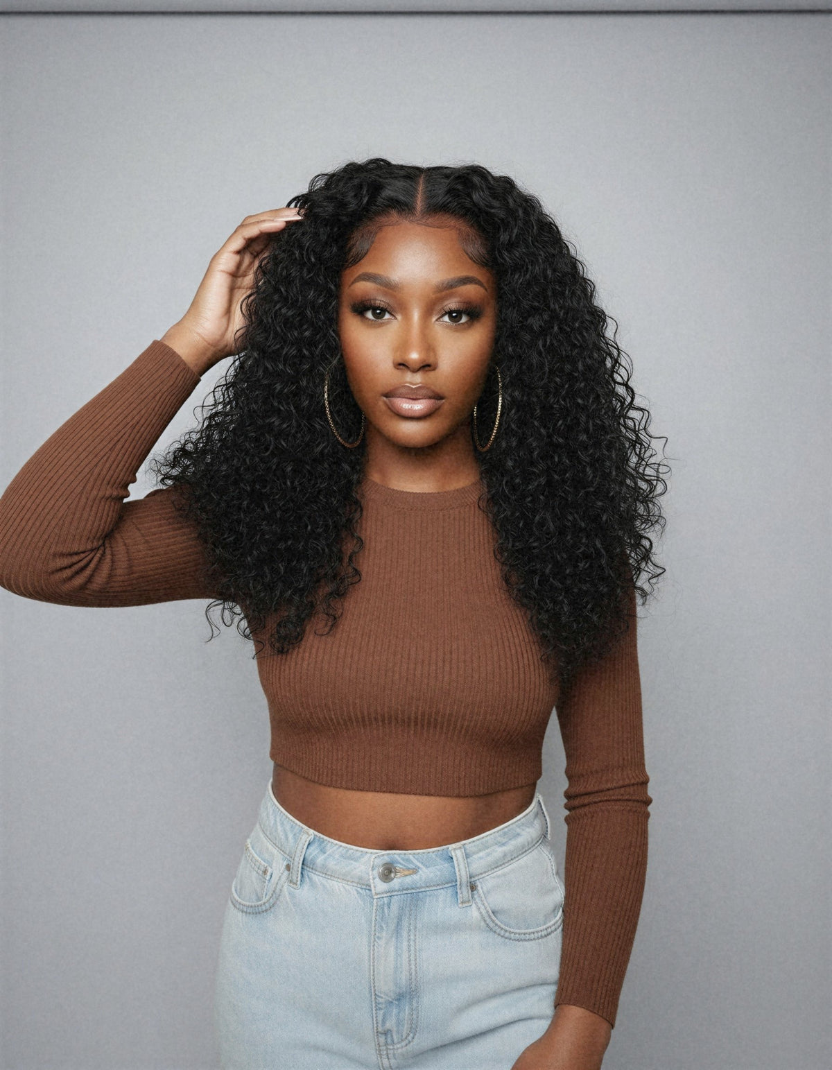 Perruque sans colle bouclée deep wave portée de face, fond studio